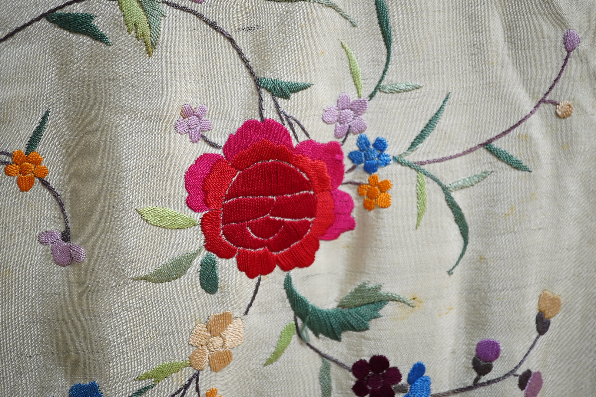 A late 19th / early 20th century Chinese cream silk and polychrome floral embroidered tasselled shawl, embroidered with a rose and floral all over design in a multitude of colours on a plain cream silk background with lo